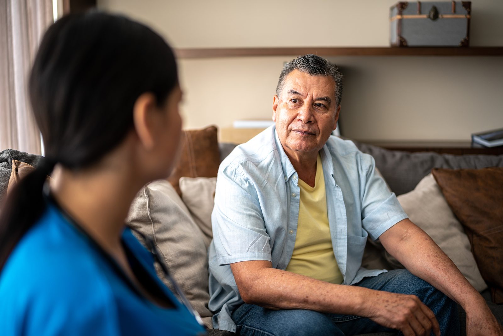 An older man talking with a nurse in his living room.